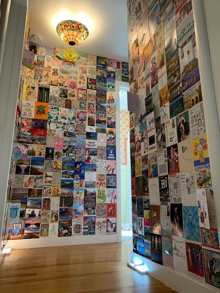 Hallway walls fully covered with colorful posters and pictures embracing more is more home decoration style.