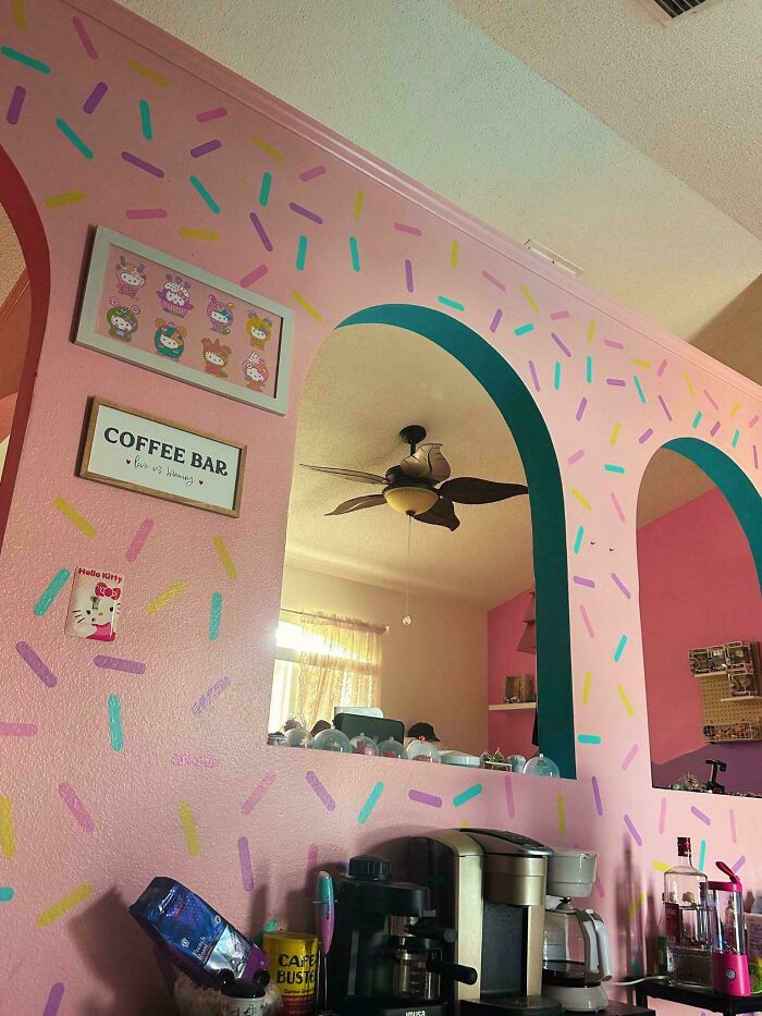 Colorful more is more home decor with pink walls, playful sprinkles pattern, coffee bar setup, and fun framed art pieces on the wall.