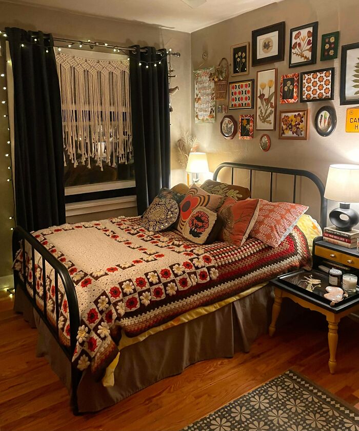 Cozy bedroom decked out with colorful pillows, floral wall art, and a crocheted blanket embracing more is more home decor.
