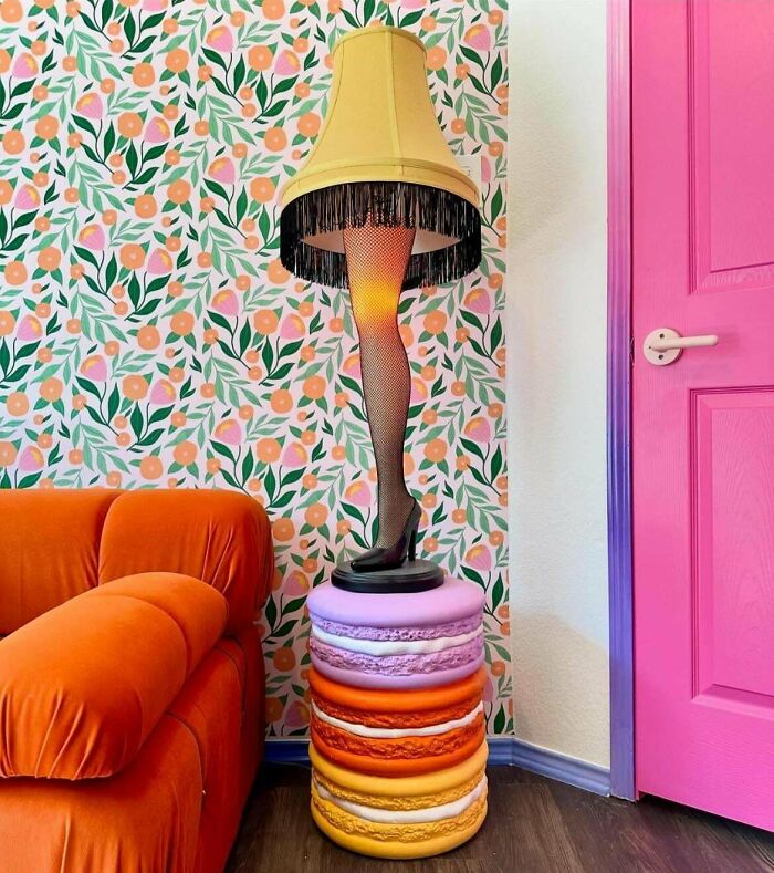 Colorful eclectic living room corner with a leg lamp on macaron stool and bold floral wallpaper, showcasing more is more home decor style.