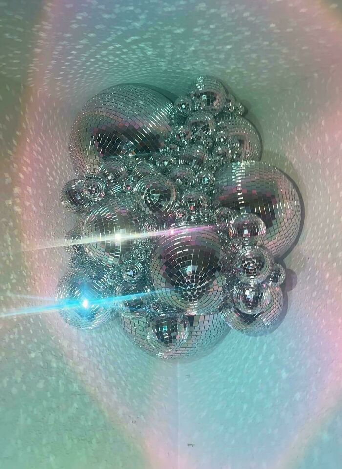 Cluster of reflective disco balls creating a sparkling light effect, showcasing more is more home decor style.