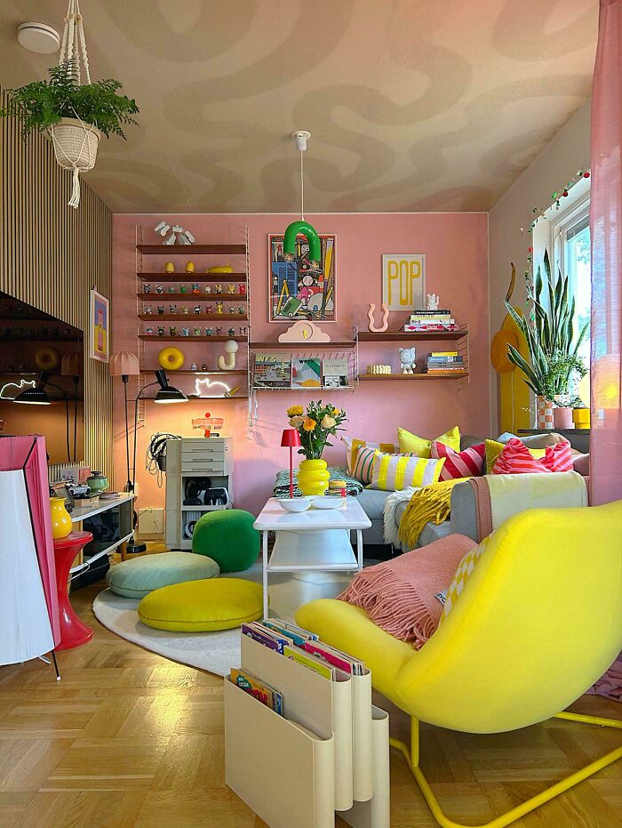 Colorful living room showcasing more is more home decor with vibrant cushions, plants, art, and eclectic furniture arrangements.