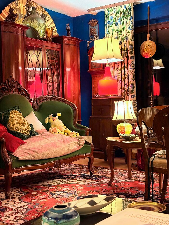 Eclectic living room showcasing more is more home decor with vibrant colors, patterned rug, vintage furniture, and decorative accents.