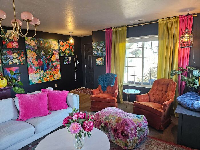 Vibrant living room with colorful floral art, bold curtains, pink cushions, and eclectic decor embracing more is more home style.