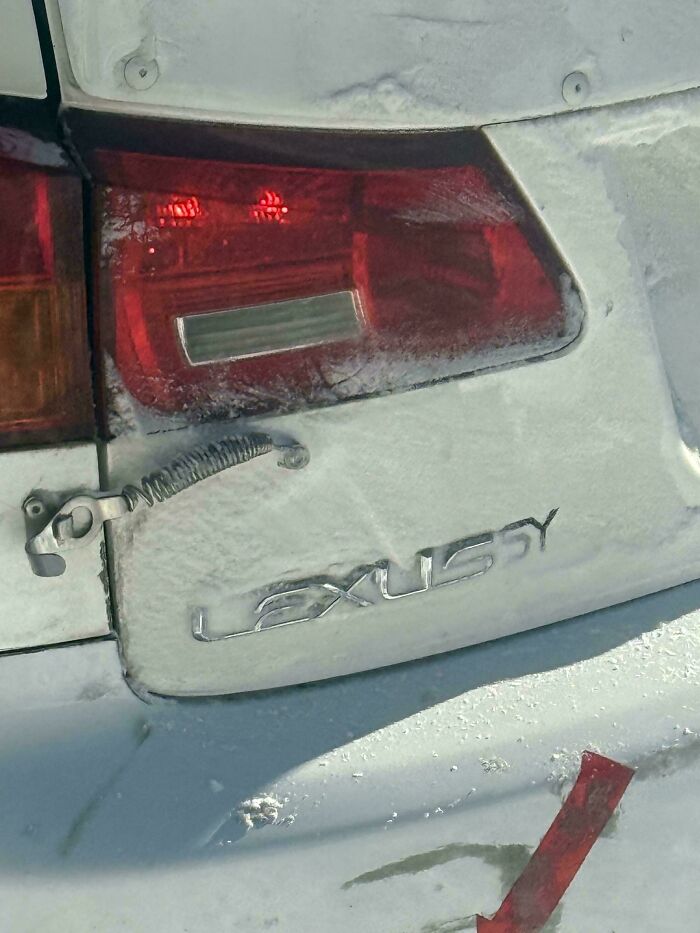 Close-up of a dirty Lexus taillight with a redneck engineering antenna fix on the snowy vehicle surface.
