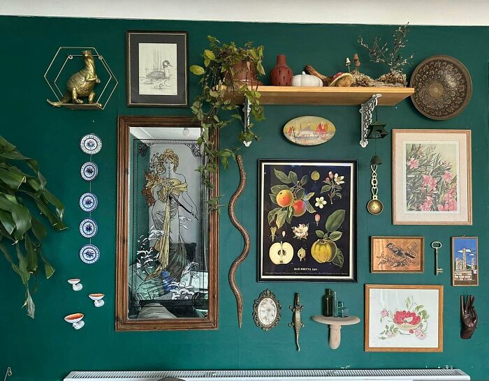 Eclectic home decor gallery wall featuring art, plants, and vintage items embracing more is more design style.