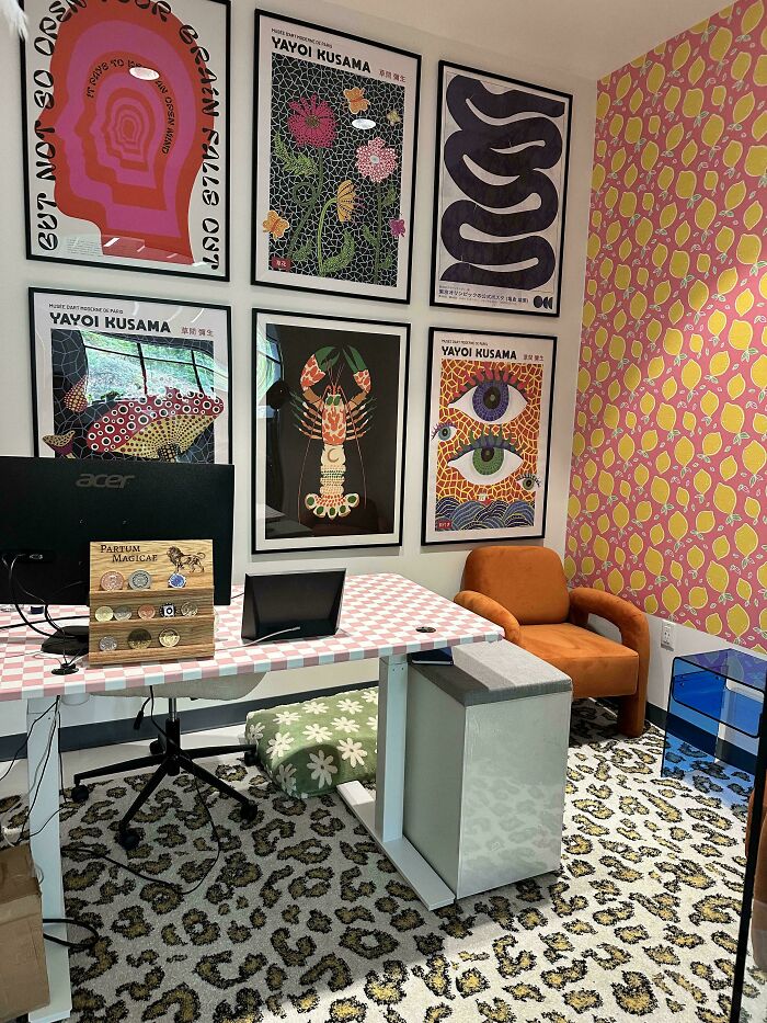 Home office decked out with colorful Yayoi Kusama art, bold patterned wallpaper, and eclectic mixed prints embracing more is more style.