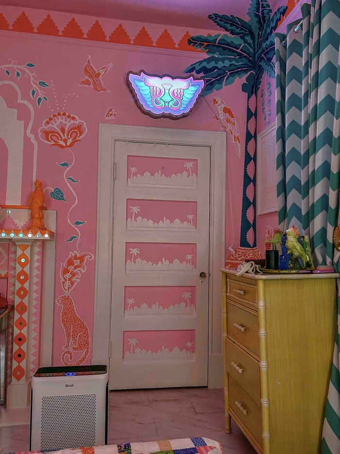 Vibrant room showcasing more is more home decor with colorful murals, patterned curtains, and eclectic decorative items.