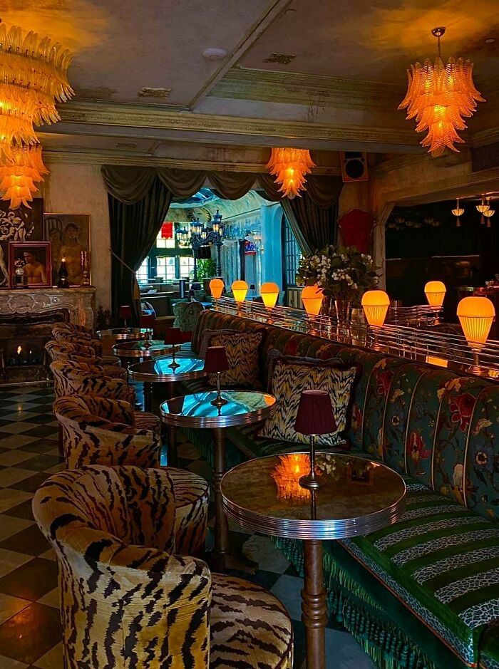 Interior of a home with bold patterned furniture, colorful cushions, and vibrant lighting showcasing more is more decor style.