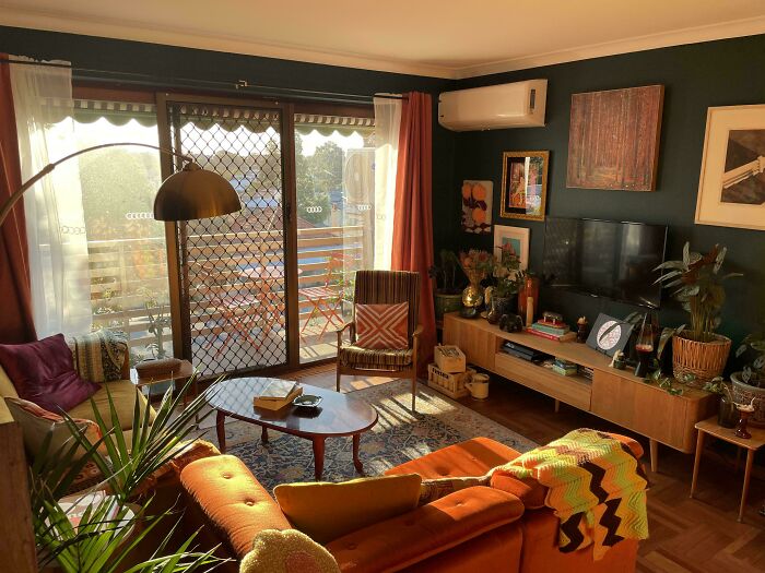 Living room decked out with colorful furniture, multiple plants, and eclectic decor embracing more is more home style.