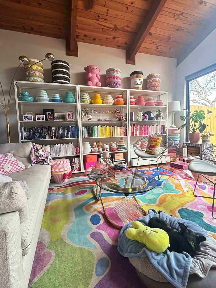 Colorful living room with decorated shelves, vibrant rug, and eclectic home decor embracing more is more style.