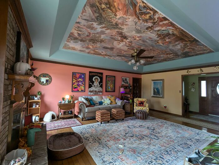 Eclectic living room with colorful decor, patterned ceiling mural, and layered textiles showcasing more is more home design.