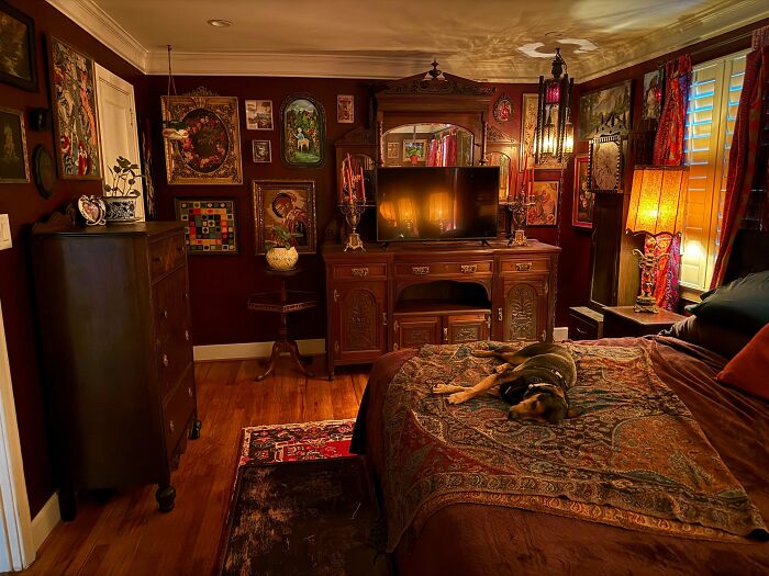 Cozy bedroom decked out with patterned textiles, vintage furniture, and walls covered in eclectic framed artwork.