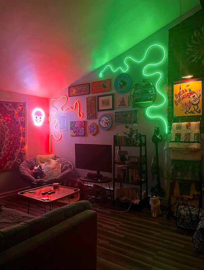 Living room decked out with colorful neon lights and eclectic wall art showcasing more is more home decor style.