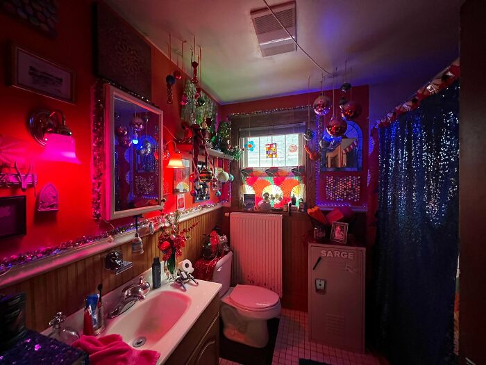 Bathroom filled with colorful decorations and eclectic lighting, showcasing a bold more is more home decor style.