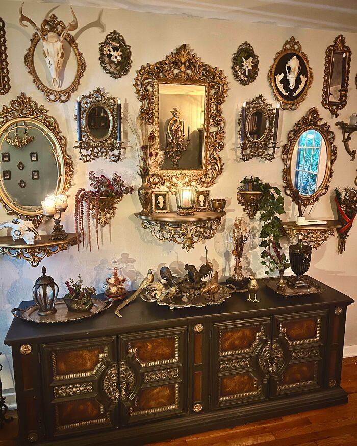 Ornate vintage mirrors and shelves with decorative skulls and candles, showcasing a more is more home decor style.