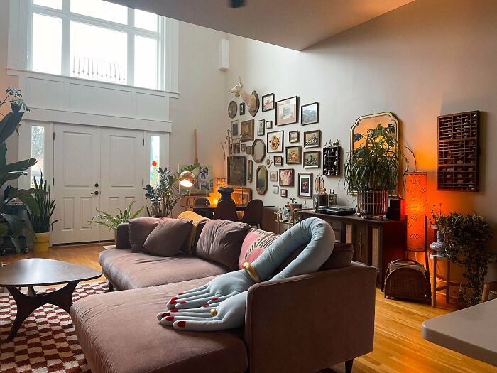 Cozy living room decked out with eclectic decor, plants, and wall art embracing the more is more home style trend.