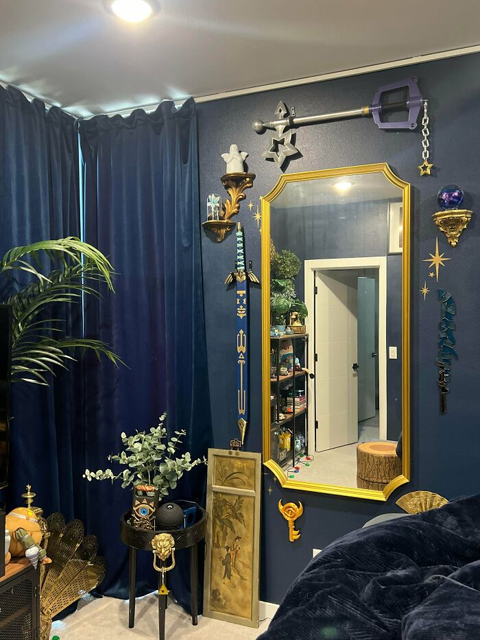 Eclectic home decor with eclectic swords, gold accents, plants, and a large mirror in a richly decorated room embracing more is more style.