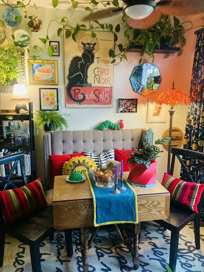 Cozy eclectic home interior featuring vibrant pillows, lush plants, colorful artwork, and layered decor embracing more is more style.