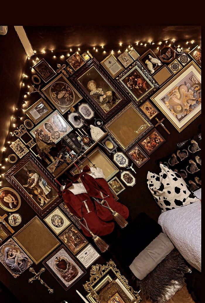 Eclectic home interior embracing more is more with numerous framed art pieces, décor, and patterned cushions on dark walls.