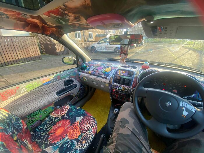 Car interior decked out with colorful stickers, floral seat covers, and bright decorations embracing more is more home style.