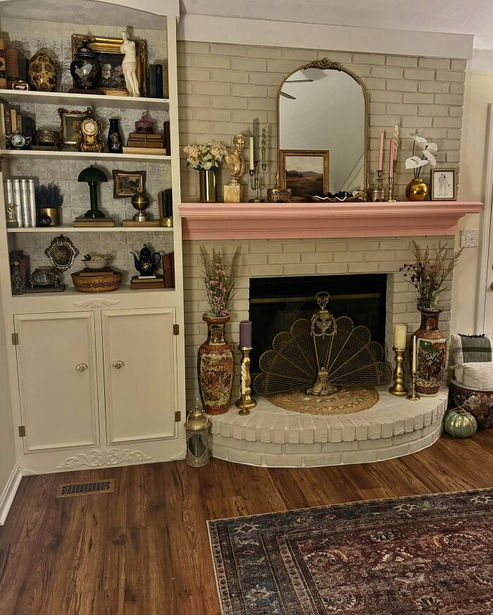 Cozy living room with an ornate fireplace and shelves filled with eclectic decor embracing more is more home style.