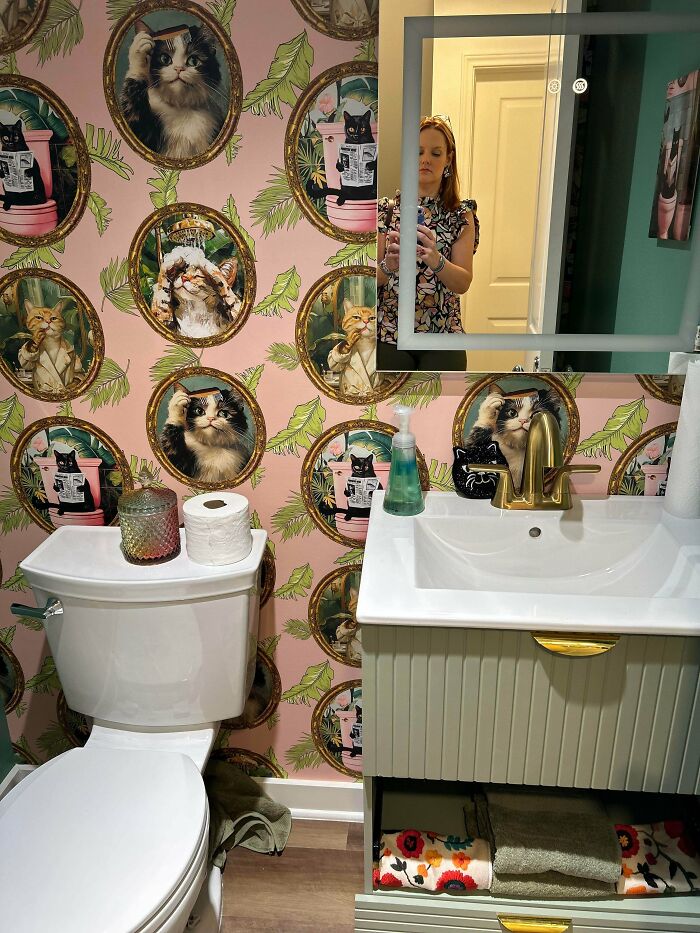 Bathroom with eclectic cat-themed wallpaper and decorative items showcasing more is more home decor style.