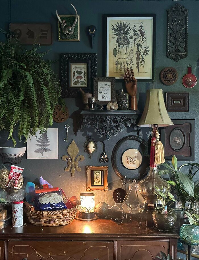 Eclectic home décor with layered wall art, plants, and vintage items showcasing a more is more interior design style.