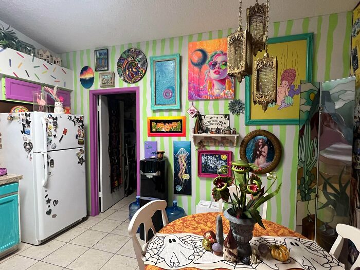 Eclectic kitchen with colorful striped walls and an array of vibrant artwork embracing more is more home decor style.
