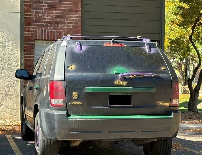 Jeep with a deeply cursed DIY project, featuring unusual purple attachments and poorly painted green accents on the rear.