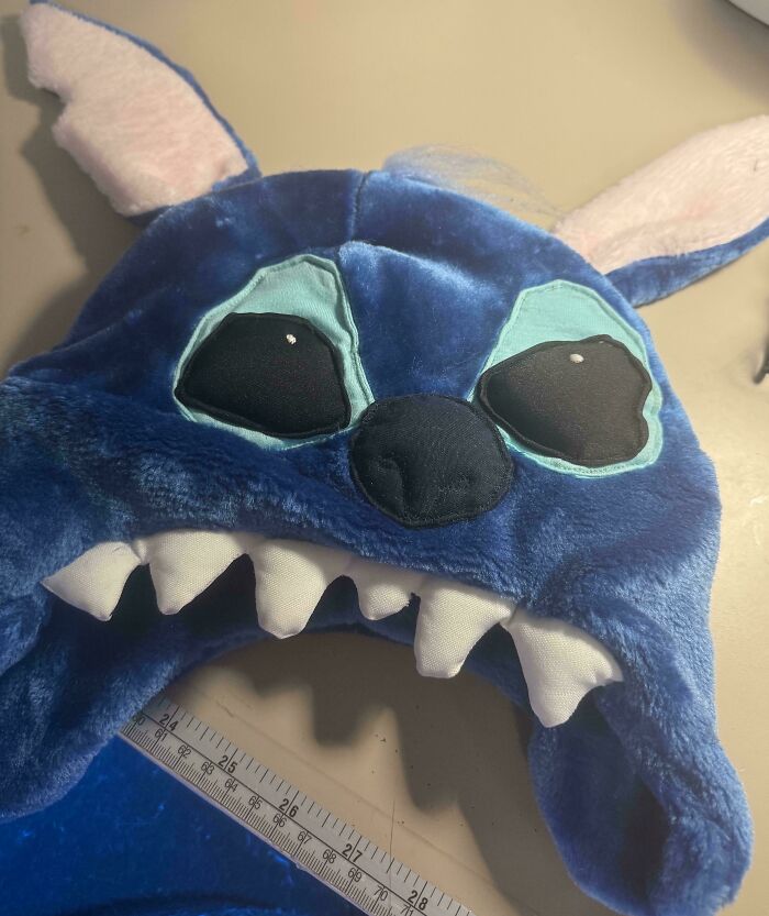 Plush blue DIY project with crooked eyes and sharp teeth, showing a deeply cursed handmade craft gone wrong.