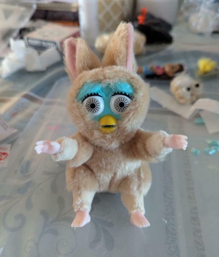 A deeply cursed DIY project showing a toy with a blue face inside a fuzzy bunny costume with small arms and legs.