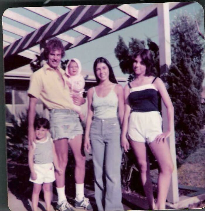 A candid old photo of a family of five posing outdoors under a pergola, revealing what the world looked like generations ago.