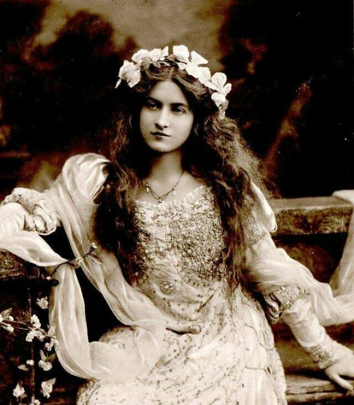 Victorian era portrait of a young woman in ornate dress and floral headpiece, showcasing period fashion and style.
