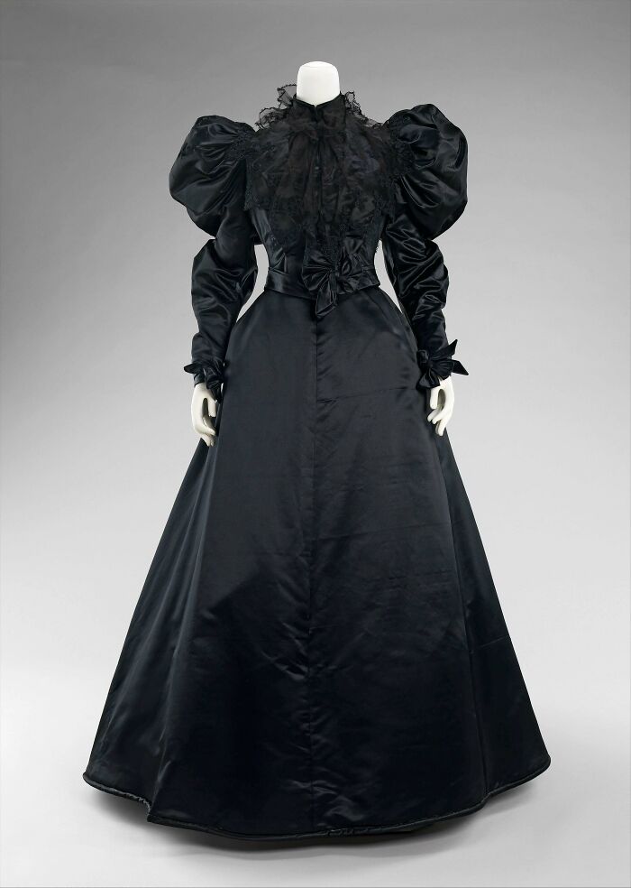 Victorian era black silk gown with puffed sleeves and lace detailing, showcasing fashion from the late 19th century period.