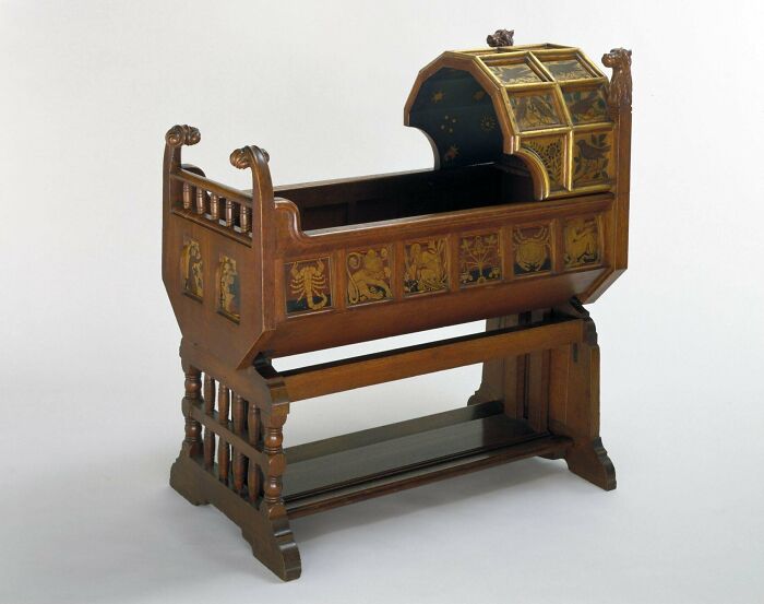 Victorian era wooden cradle with intricate zodiac designs and detailed craftsmanship reflecting the period style.