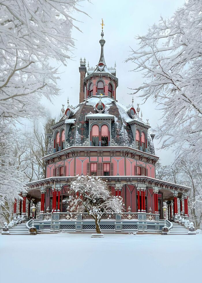 Victorian era house covered in snow with ornate architecture and frosted trees surrounding the period building in winter.