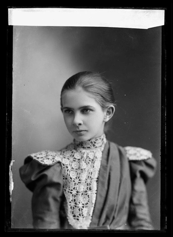 Young woman in Victorian era dress with lace collar in a black and white Victorian era photo portrait.