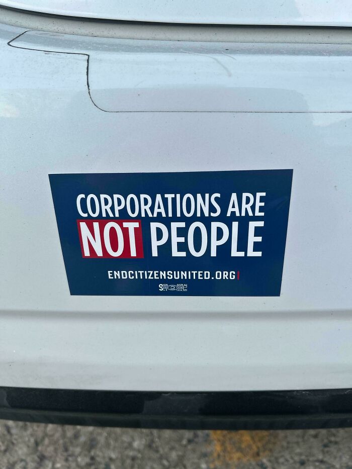 Bumper sticker on white vehicle stating corporations are not people