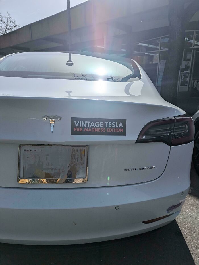 White Tesla car with a vintage Tesla pre-madness edition bumper sticker on the rear