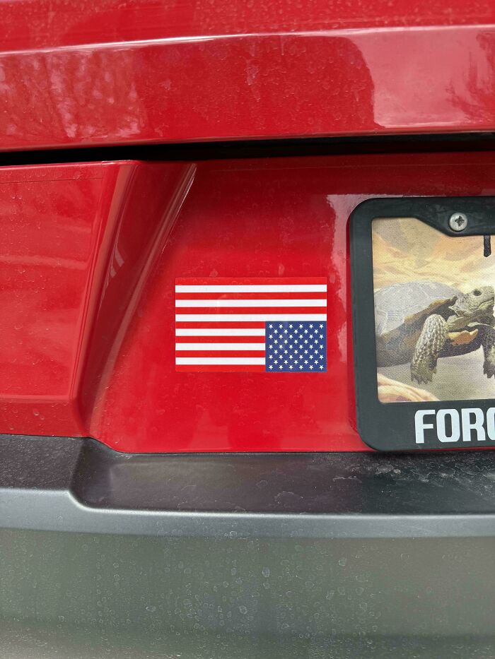 Red car with upside-down American flag bumper sticker