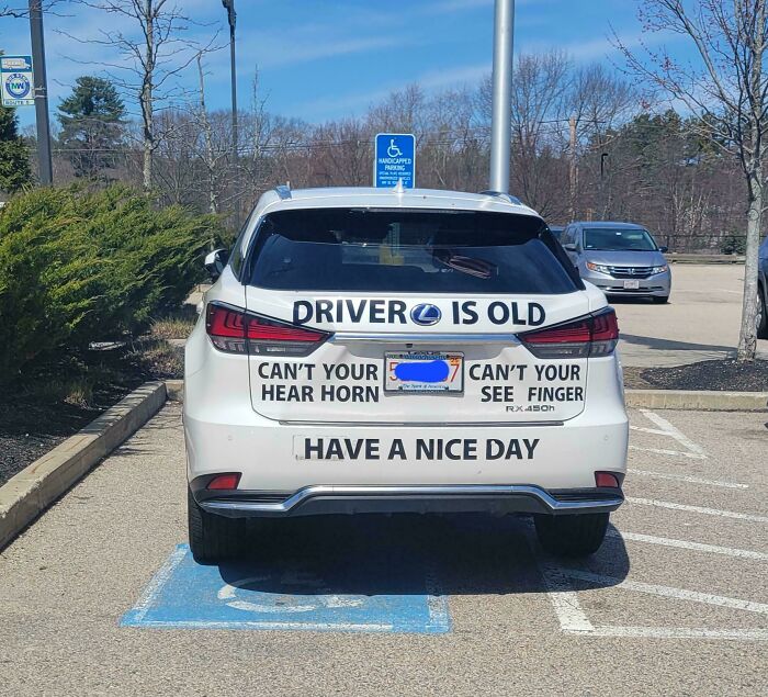 Funny old driver bumper sticker on white Lexus at handicapped parking spot