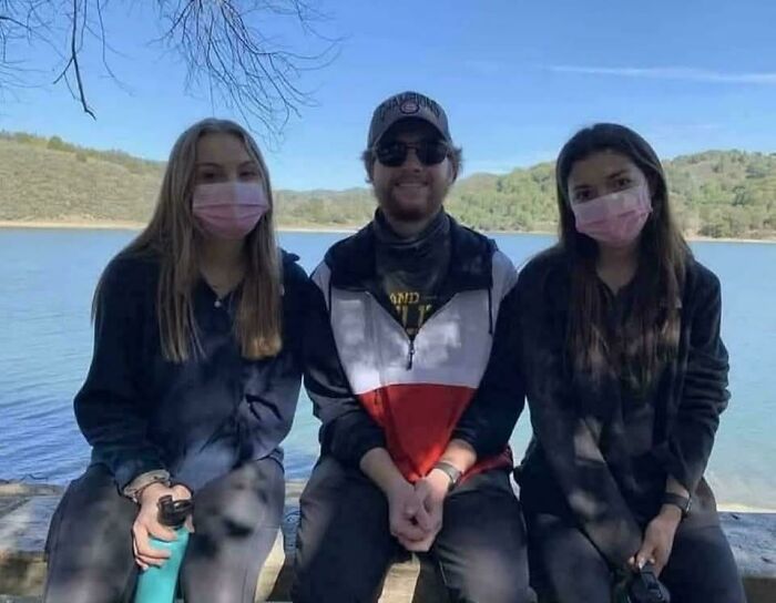 Three people wearing masks sitting by a lake, creating a misleading and confusing photo that seems like a glitch in real life.