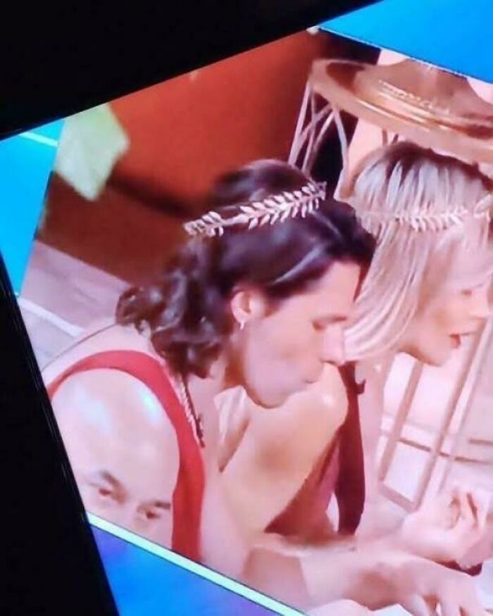 Two people wearing headbands in close conversation with a third person's face appearing oddly positioned, creating a misleading photo effect.