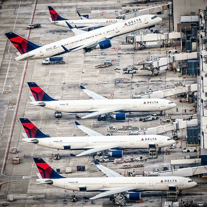 Multiple Delta airplanes at airport gates with one airplane seemingly tilted as a misleading photo glitch.