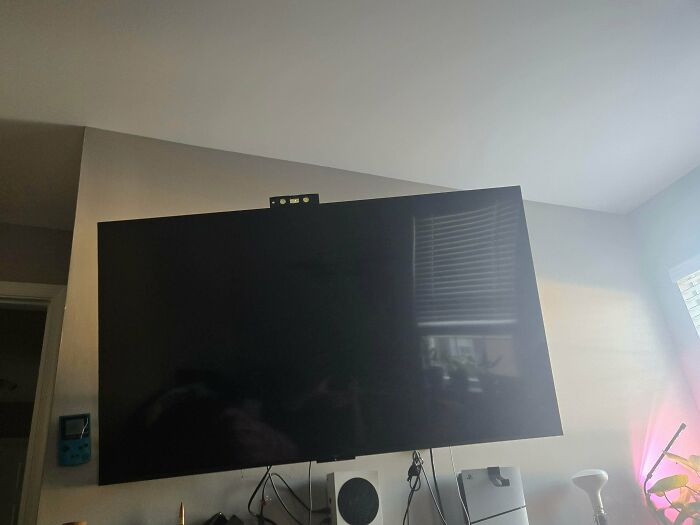 Large flat screen TV mounted in living room appearing to float, creating a misleading and confusing photo glitch effect.