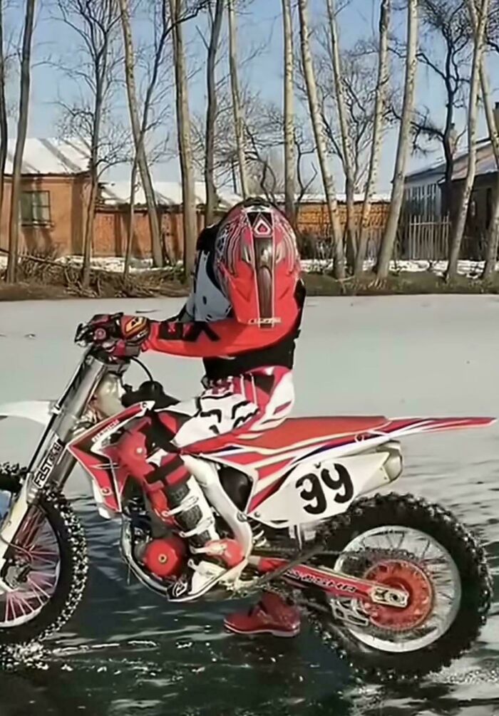 Motorcyclist on a red dirt bike appears headless, creating a misleading and confusing real-life glitch photo effect.