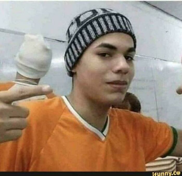 Young man in an orange shirt and striped beanie making a gesture with his hands in a misleading and confusing photo.