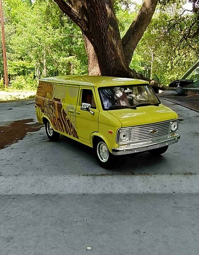 Yellow vintage van parked under a tree creating a misleading and confusing photo that seems like a glitch in real life.