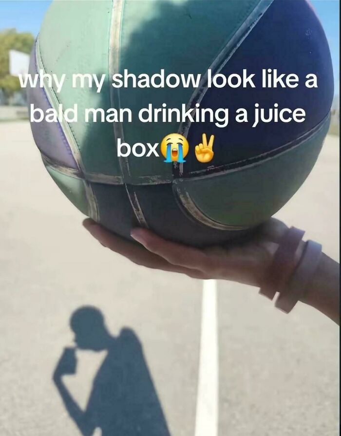 Shadow on pavement looks like a bald man drinking from a juice box, creating a misleading and confusing photo illusion.